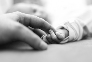 infant holding mother's hand